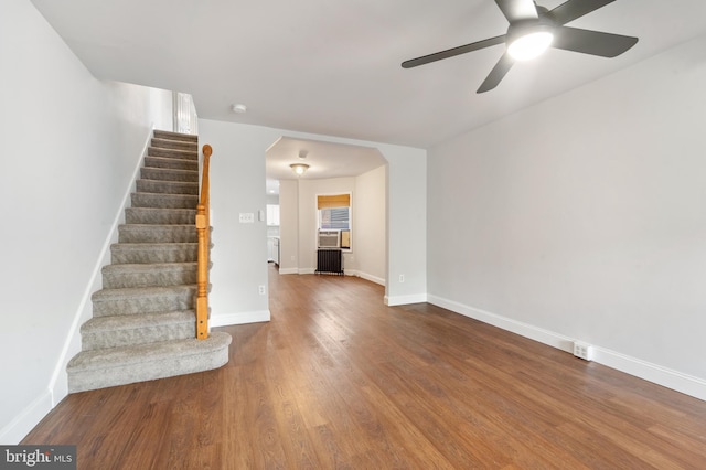 41 Bellevue Ter, Collingswood, NJ 08108 - unfurnished living room featuring a ceiling fan, stairs, wood finished floors, radiator heating unit, and arched walkways