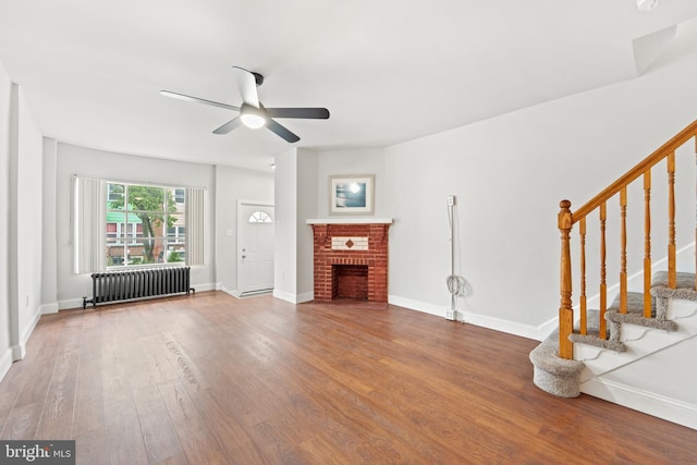 41 Bellevue Ter, Collingswood, NJ 08108 - unfurnished living room featuring radiator, stairs, wood finished floors, a ceiling fan, and a brick fireplace