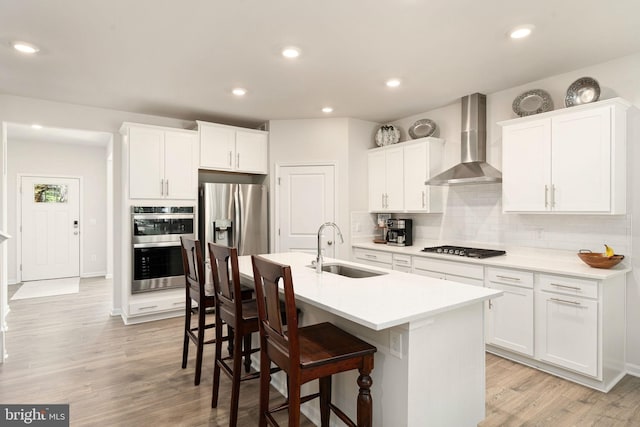 610 Long Meadow Dr, Fredericksburg, VA 22406 - kitchen with wall chimney exhaust hood, a sink, stainless steel appliances, a kitchen bar, and light wood-style flooring