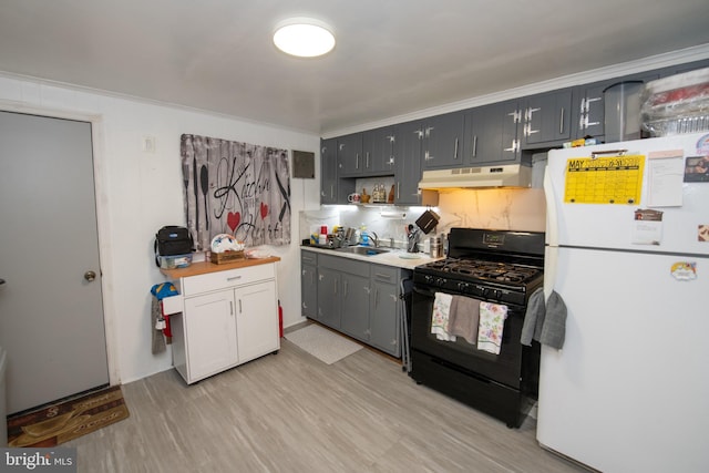 3444 G St, Philadelphia, PA 19134 - kitchen with freestanding refrigerator, black gas stove, under cabinet range hood, a sink, and light wood finished floors