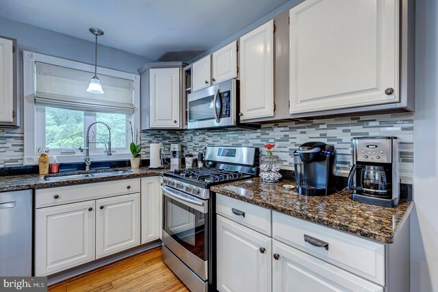 14298 S Union Church Rd, Ellendale, DE 19941 - kitchen with stainless steel appliances, a sink, white cabinetry, backsplash, and decorative light fixtures