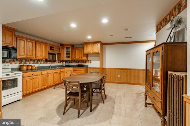 290 S Windy Mansion Rd, Denver, PA 17517 - kitchen with white electric stove, black microwave, a wainscoted wall, glass insert cabinets, and brown cabinetry