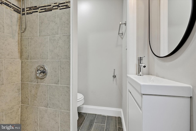 406 S Eaton St, Baltimore, MD 21224 - bathroom with a tile shower, toilet, vanity, wood finish floors, and baseboards