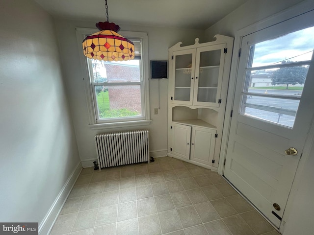 unfurnished dining area with radiator heating unit, light tile patterned flooring, and baseboards