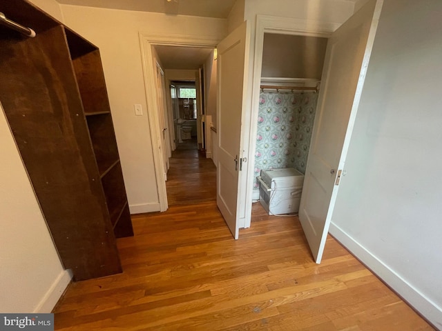 hall with light wood-style floors and baseboards