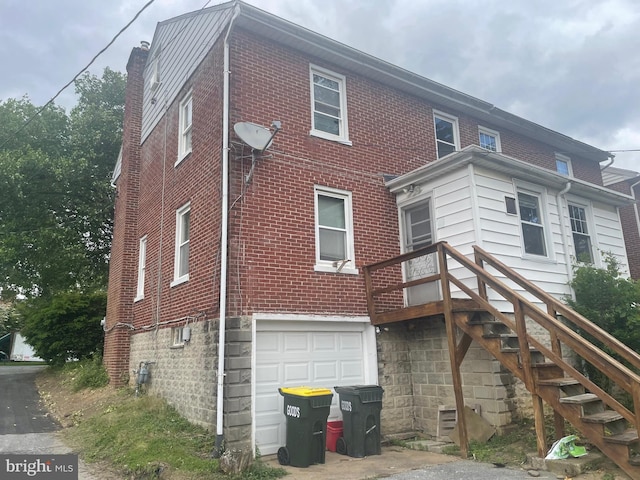 rear view of property with a garage and brick siding