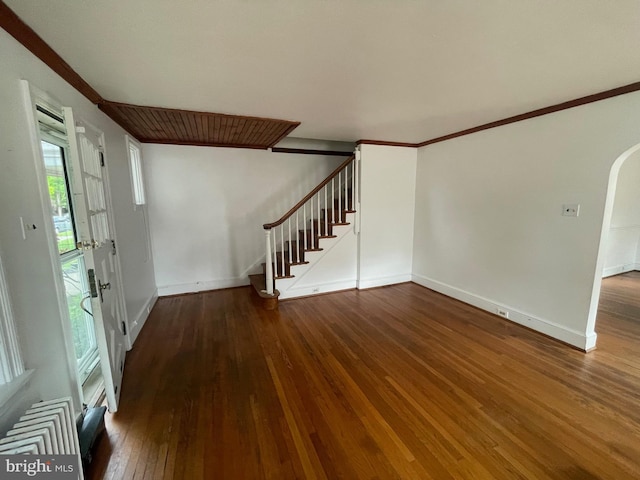 foyer entrance featuring stairs, hardwood / wood-style flooring, baseboards, ornamental molding, and arched walkways