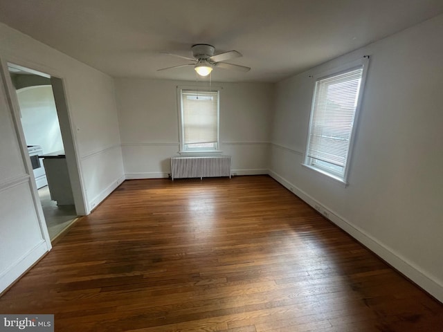 spare room with radiator heating unit, ceiling fan, hardwood / wood-style floors, and baseboards