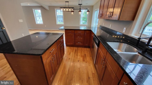 kitchen with light wood finished floors, brown cabinetry, a peninsula, hanging light fixtures, and dark stone counters