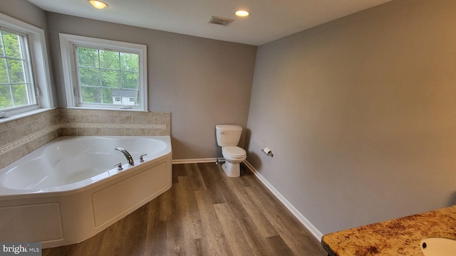 bathroom with wood finished floors, toilet, a bath, recessed lighting, and baseboards