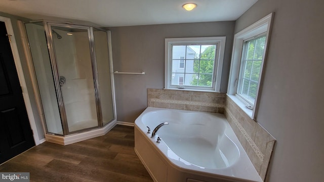 full bathroom with wood finished floors, a stall shower, and a bath
