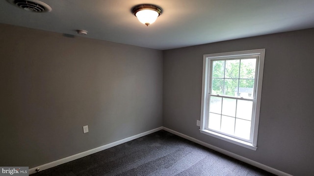 empty room with baseboards and dark carpet