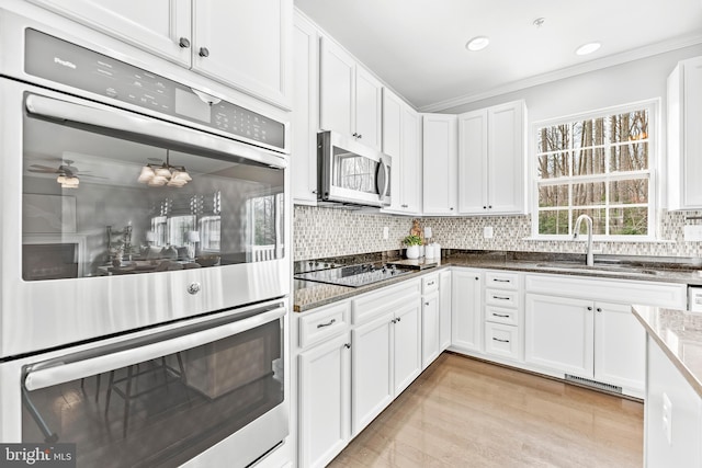 1983 Foxwood Ln, Lusby, MD 20657 - kitchen featuring stainless steel appliances, a sink, crown molding, white cabinetry, and dark stone counters