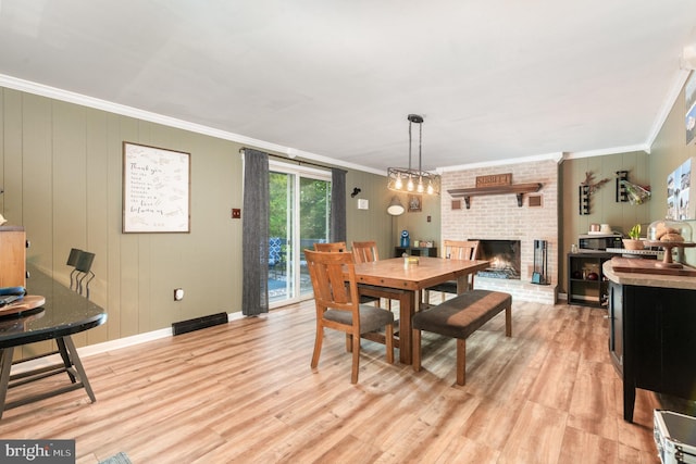 dining area with crown molding, light wood finished floors, a fireplace, and baseboards