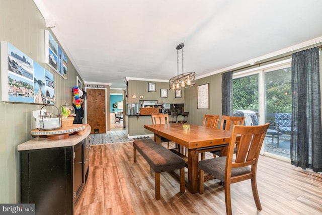 dining area with light wood finished floors, crown molding, and a chandelier