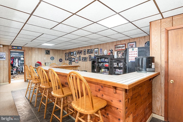 indoor dry bar with wood walls, a paneled ceiling, and carpet flooring