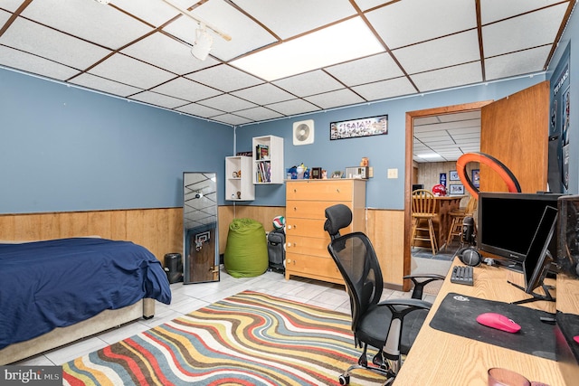 bedroom featuring a paneled ceiling, wooden walls, wainscoting, and a desk
