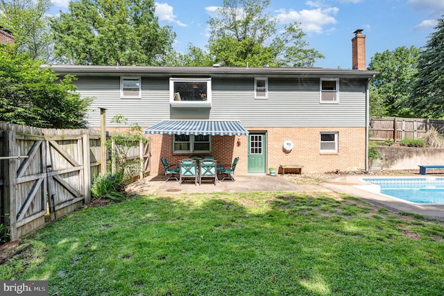 back of property with brick siding, a patio area, and a chimney