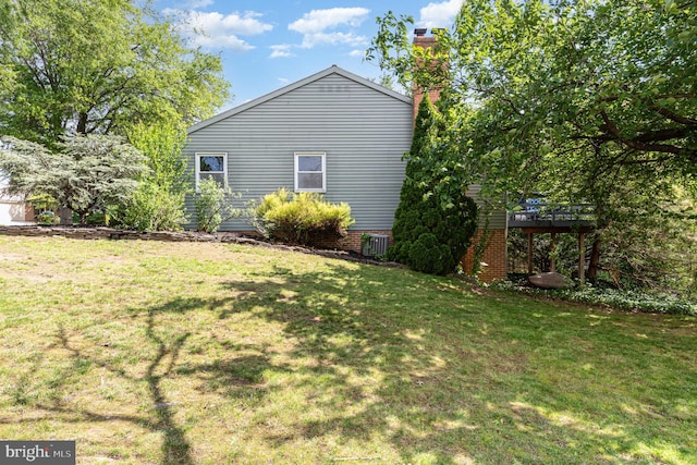 view of side of property with a yard, a chimney, and a deck