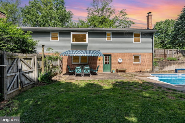 rear view of property with brick siding, a patio area, and a chimney