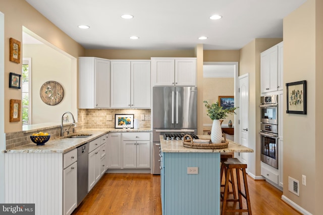 21381 Chickacoan Trail Dr, Broadlands, VA 20148 - kitchen featuring appliances with stainless steel finishes, a sink, a kitchen bar, light stone countertops, and recessed lighting