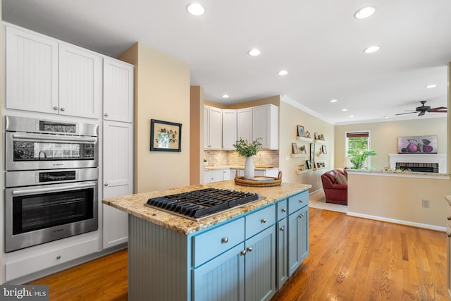 21381 Chickacoan Trail Dr, Broadlands, VA 20148 - kitchen with stainless steel appliances, open floor plan, recessed lighting, light wood-style flooring, and blue cabinets