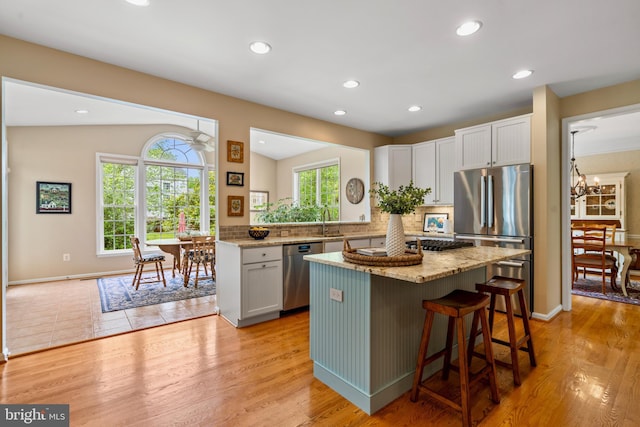 21381 Chickacoan Trail Dr, Broadlands, VA 20148 - kitchen featuring appliances with stainless steel finishes, a kitchen island, light stone countertops, decorative backsplash, and recessed lighting