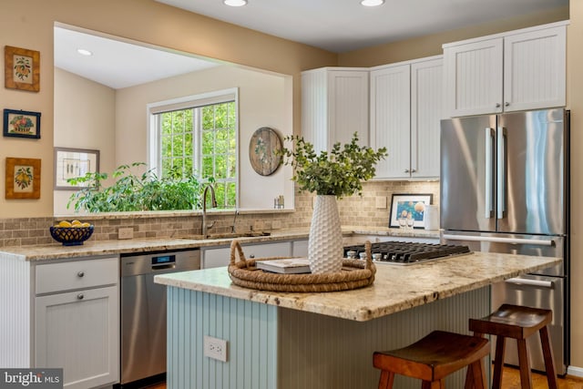 21381 Chickacoan Trail Dr, Broadlands, VA 20148 - kitchen with appliances with stainless steel finishes, a sink, a breakfast bar area, light stone counters, and decorative backsplash