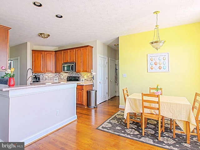 551 N Buckton Rd, Middletown, VA 22645 - kitchen featuring stainless steel microwave, wood finished floors, backsplash, brown cabinets, and a textured ceiling