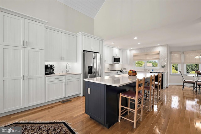 30558 Luff Ln Unit C-14, Ocean View, DE 19970 - kitchen featuring appliances with stainless steel finishes, backsplash, light wood-style floors, white cabinetry, and high vaulted ceiling