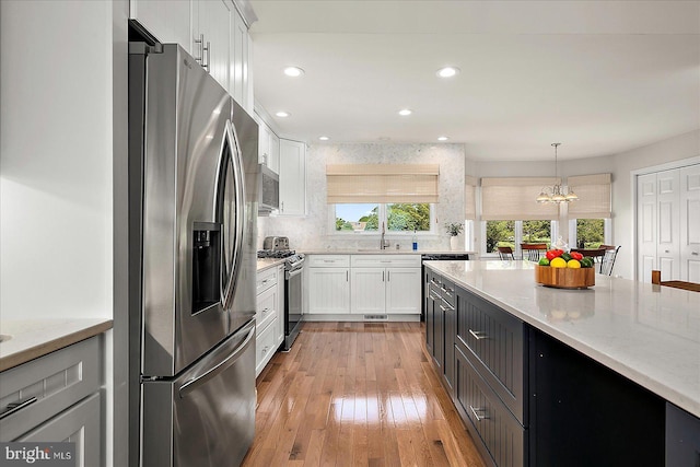 30558 Luff Ln Unit C-14, Ocean View, DE 19970 - kitchen featuring appliances with stainless steel finishes, a sink, white cabinets, light stone countertops, and decorative light fixtures