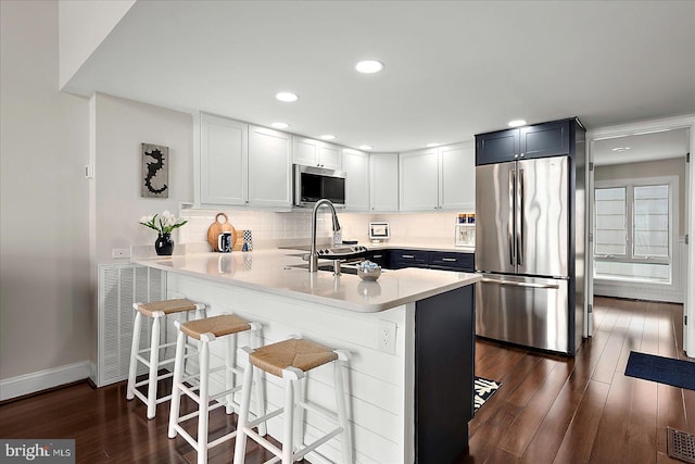 3 129th St Unit 7, Ocean City, MD 21842 - kitchen with stainless steel appliances, dark wood-style flooring, light countertops, baseboards, and a breakfast bar area