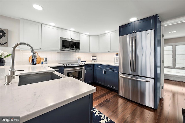 3 129th St Unit 7, Ocean City, MD 21842 - kitchen featuring appliances with stainless steel finishes, a sink, blue cabinetry, dark wood-style flooring, and decorative backsplash