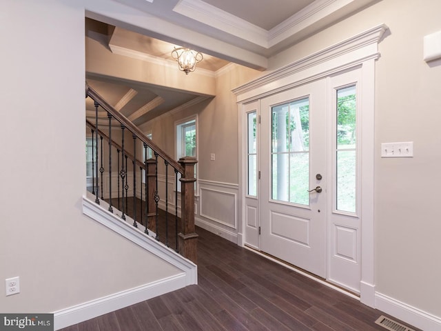 foyer featuring plenty of natural light, crown molding, stairs, wood finished floors, and a chandelier