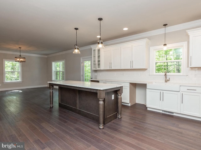 kitchen with a sink, white cabinets, a kitchen bar, light countertops, and tasteful backsplash