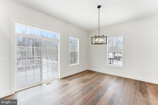 unfurnished dining area featuring a chandelier, wood finished floors, and baseboards