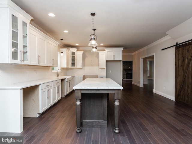kitchen featuring a sink, crown molding, glass insert cabinets, backsplash, and white cabinetry