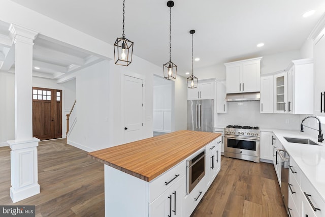 kitchen with high quality appliances, a sink, under cabinet range hood, dark wood-style floors, and a kitchen island