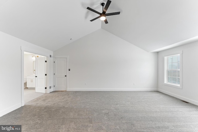 carpeted spare room with a ceiling fan, vaulted ceiling, and baseboards