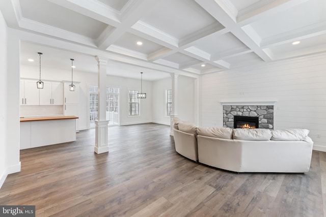 living room featuring dark wood-style floors, a stone fireplace, coffered ceiling, recessed lighting, and beam ceiling