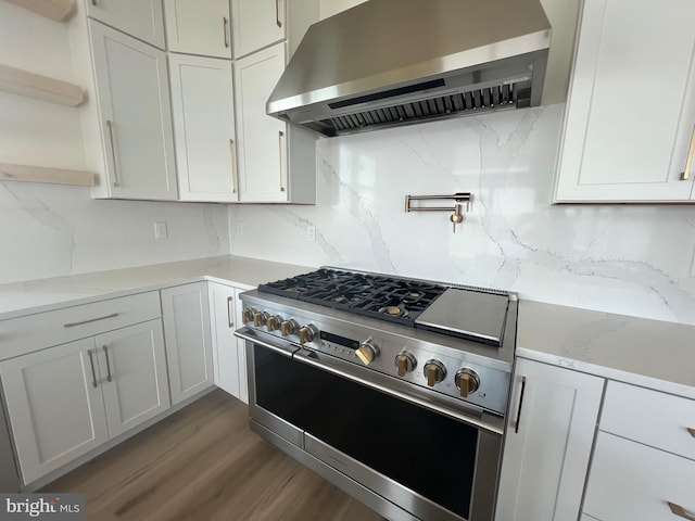 kitchen with extractor fan, high end stainless steel range, open shelves, tasteful backsplash, and wood finished floors