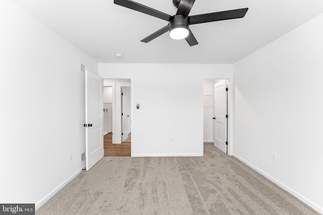unfurnished bedroom featuring carpet flooring, baseboards, a spacious closet, and a ceiling fan