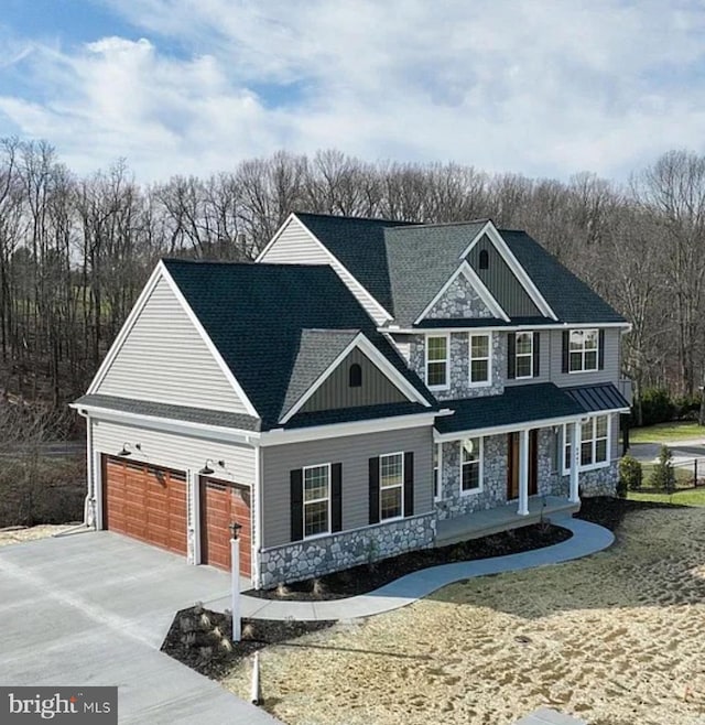 view of front of property featuring stone siding, a porch, a garage, and driveway