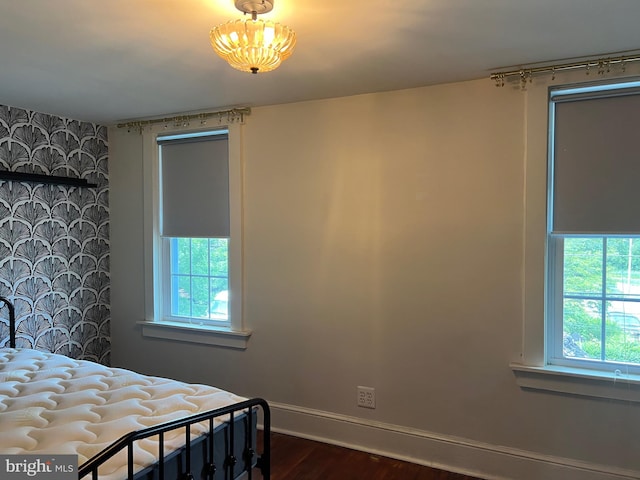 303 Johnson Ave, Upper Chichester, PA 19061 - bedroom featuring multiple windows, baseboards, an accent wall, dark wood-type flooring, and wallpapered walls