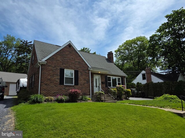 616 Sylvan Pl, Harrisburg, PA 17109 - view of front of house with a chimney, brick siding, a front lawn, and roof with shingles