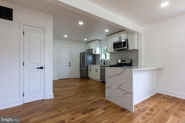 2 Baltimore Ave, Glen Burnie, MD 21061 - kitchen featuring appliances with stainless steel finishes, decorative backsplash, light wood-style flooring, white cabinetry, and baseboards
