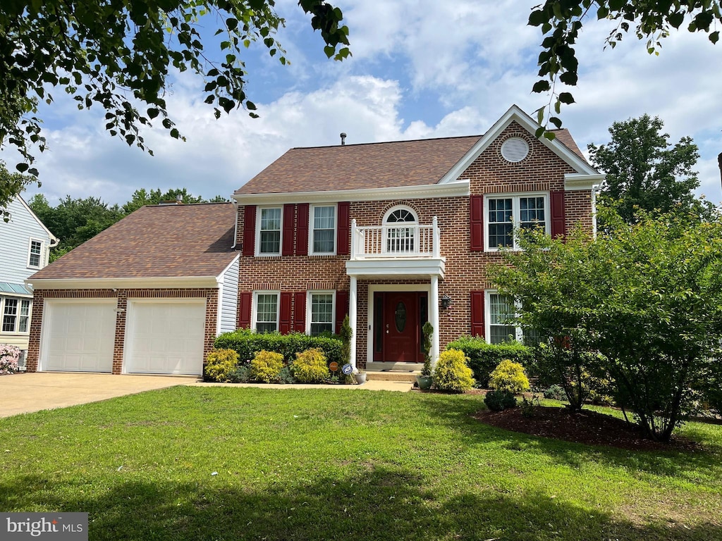 colonial house featuring a garage, brick siding, a front yard, and concrete driveway