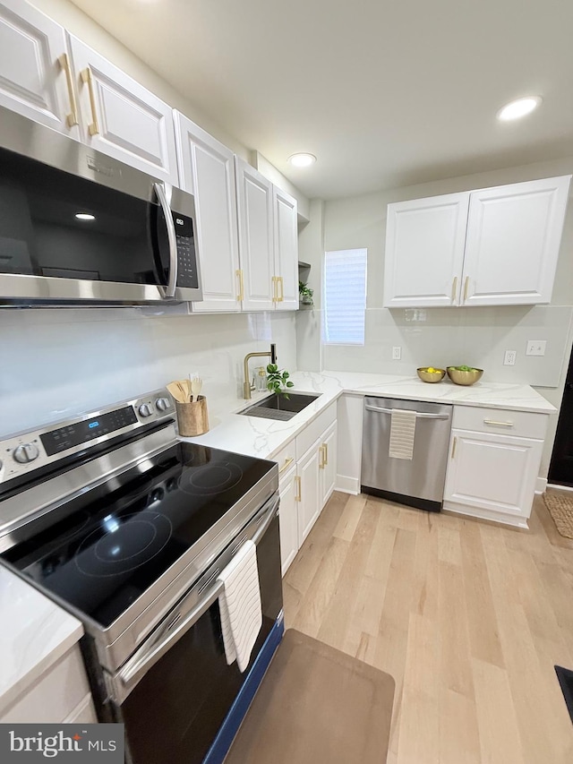 2112 Llewelyn Ave, Baltimore, MD 21213 - kitchen with appliances with stainless steel finishes, a sink, white cabinetry, light wood-style floors, and recessed lighting