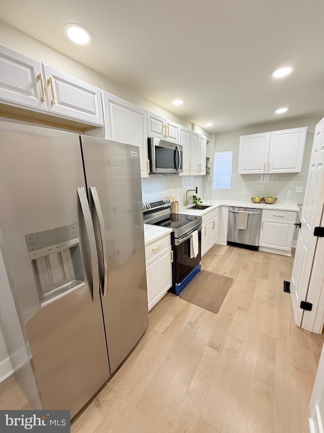 2112 Llewelyn Ave, Baltimore, MD 21213 - kitchen featuring appliances with stainless steel finishes, a sink, white cabinets, light wood-type flooring, and light countertops