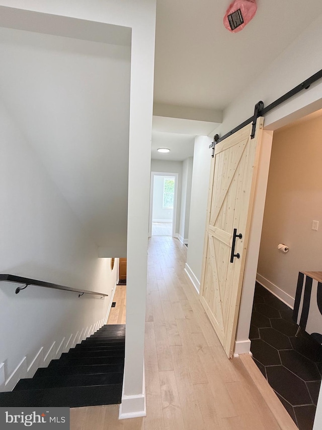 2112 Llewelyn Ave, Baltimore, MD 21213 - stairs featuring a barn door, wood finished floors, and baseboards